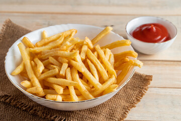 Hot golden french fries with ketchup on a wooden background. Tasty american fast food.