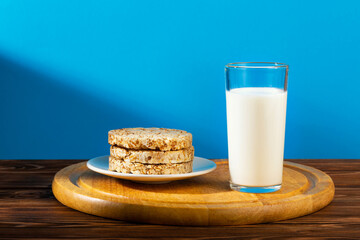 A glass of milk and cookies on a wooden table on a blue background.