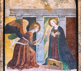 Close-up on colorful medieval religious fresco showing an angel talking to Virgin Mary