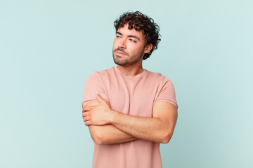 hispanic handsome man shrugging, feeling confused and uncertain, doubting with arms crossed and...