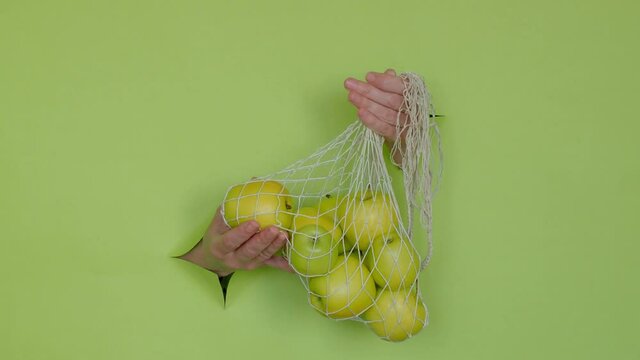 green apples in a string bag, on a green background