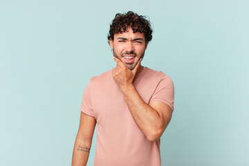 hispanic handsome man with mouth and eyes wide open and hand on chin, feeling unpleasantly shocked,...