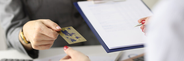 Employee gives the client plastic bank card and document for signature