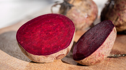Beetroot cut in half on wooden cutting board, displaying its vibrant red color in the bright sun...