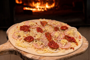 Raw Brazilian style pizza entering the wood oven