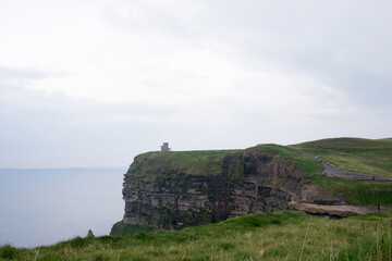 Fototapeta na wymiar Cliffs at Moher on a rainy day. Green fields and ancient tower.