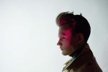 portrait of a young stylish brutal guy in a light coat, dark-haired European appearance close-up,...