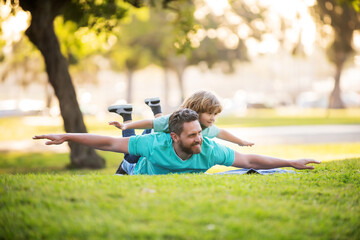 Father lying on grass, with excited happy little child son on shoulder. Weekend man family concept. Carefree two man generations family.
