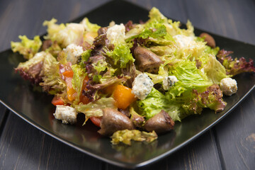 Chicken hearts lettuce leaves cheese laid out in a plate dressed with sauce