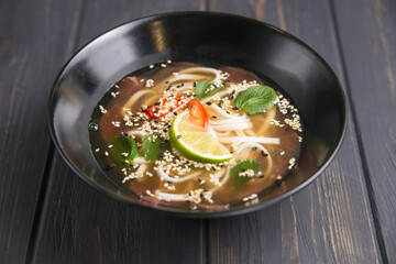 Vietnamese soup with veal noodles in broth decorated with lime stands on the table