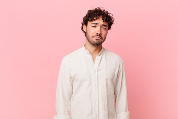 hispanic handsome man feeling sad and whiney with an unhappy look, crying with a negative and...