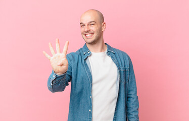 bald man smiling and looking friendly, showing number four or fourth with hand forward, counting...