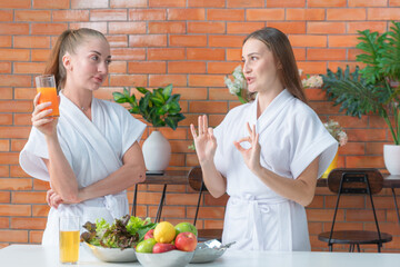 two women in bathrobe cooking a morning food vegetable salad at pantry preparing at home. A...
