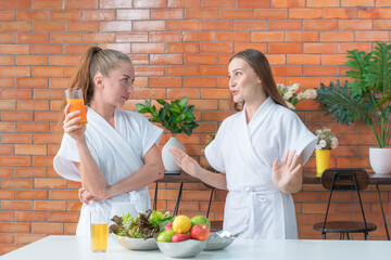 two women in bathrobe cooking a morning food vegetable salad at pantry preparing at home. A...