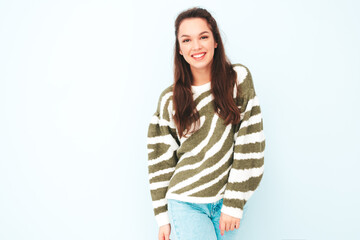 Young beautiful smiling female in trendy summer hipster clothes. Sexy carefree woman posing near light blue wall in studio. Positive model having fun indoors. Cheerful and happy