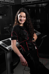 Girl in EMS suit in gym. Sport training in electrical muscle stimulation suit.