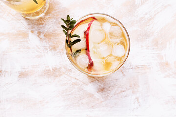 Fresh and healthy cocktail or mocktail with apple, ice, cinnamon and herbs. Refreshing summer drink. Light and shadows. Top view.