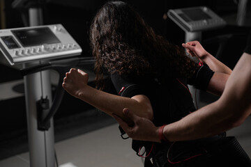 Girl in EMS suit in gym. Sport training in electrical muscle stimulation suit.