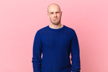 bald man looking puzzled and confused, biting lip with a nervous gesture, not knowing the answer to...