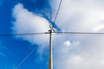 Straßenlaterne an einem Holzmasten mit Stromleitungen