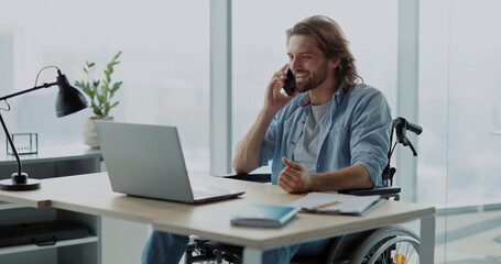 Handsome young invalid disabled man business guy talking on mobile phone in contemporary office. Worker. Person with disabilities. Phone call.