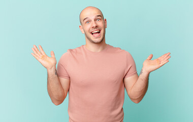bald man feeling happy, excited, surprised or shocked, smiling and astonished at something...