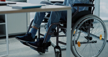 Young man in black wheelchair moving along the corporate office. Employee business person with...