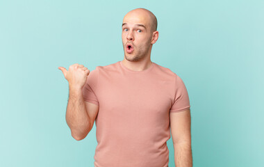 bald man looking astonished in disbelief, pointing at object on the side and saying wow,...