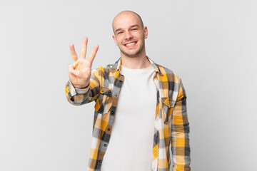 bald man smiling and looking friendly, showing number three or third with hand forward, counting...