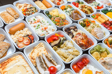 Airplane food presentation with variety of in flight meals.  Flight catering.  Food on airplanes. Salad bar buffet  display in restaurant.  Meat cuts. Hot appetizers. Close-up, a lot of food.
