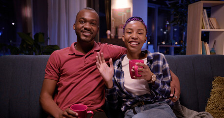 Face portrait of beautiful young african family man and woman drinking tea communicating videochat laptop webcam conversation with friends. Apartment.