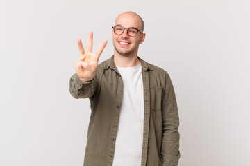 bald man smiling and looking friendly, showing number three or third with hand forward, counting...