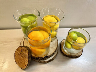Four jugs full of water with lemons and oranges with tree trunks