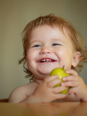 Laughing cute child eating apple fruit, portrait on blurred background. Enjoy eating moment. Healthy food and kid concept. Funny child face closeup.