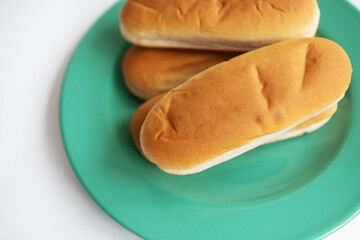 Fresh hot dog buns which lie on a green plate. Top view, close-up.