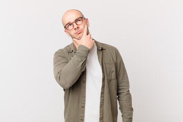 bald man thinking, feeling doubtful and confused, with different options, wondering which decision...