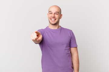 bald man pointing at camera with a satisfied, confident, friendly smile, choosing you