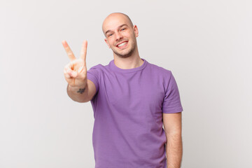 bald man smiling and looking friendly, showing number two or second with hand forward, counting down