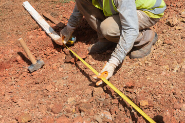 Operário medindo com trena futura obra de calçada em área industrial, Paraná, Brasil. 