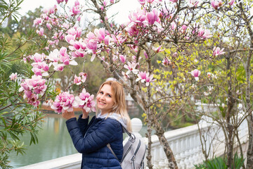 beautiful woman near a blooming magnolia tree smiling looking at camera © Юля Шевцова