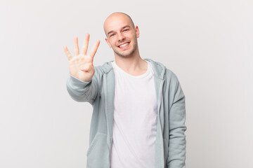 bald man smiling and looking friendly, showing number four or fourth with hand forward, counting...