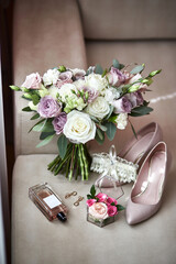 bridal accessories such as shoes, bouquet , ring and perfume lie on a table