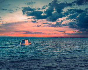 an old fishing ship in the sea during this magic sunset