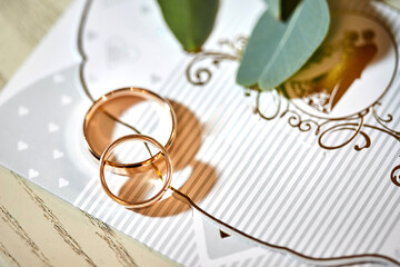 beautiful wedding rings lie on invitation card