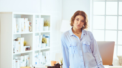 Portrait of smiling young woman with dslr photo camera standing in loft apartment