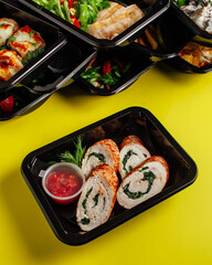 Healthy lunch at the workplace. Pick up food in black containers with cutlery