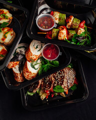 Healthy lunch at the workplace. Pick up food in black containers with cutlery