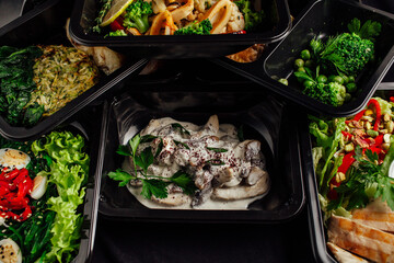 Healthy lunch at the workplace. Pick up food in black containers with cutlery