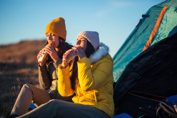 Hikers eating food near tent at mountain