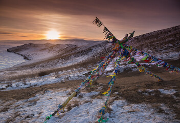 Colored ritual ribbons tied on the tree and wooden poles as a buddhist tradition on Baikal lake